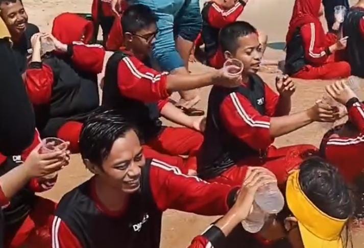 sekelompok peserta ppsdsn pendowo kudus sedang mengikuti permainan di luar ruangan, dengan beberapa peserta saling menuangkan air dan melakukan aktivitas bersama.